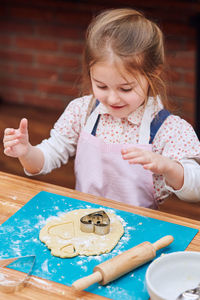 High angle view of cute girl making cookies on table at home