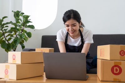 Young woman using laptop while sitting on sofa at home