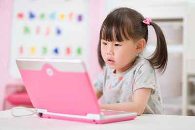 Cute girl looking at camera while sitting on table