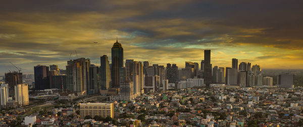 Aerial view of buildings in city against cloudy sky