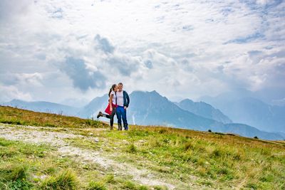 Woman with umbrella on mountain against sky