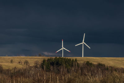 Wind turbines on field against sky