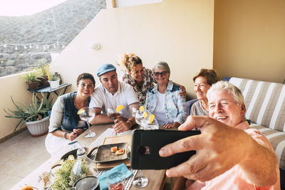 Man taking selfie while family having food at home