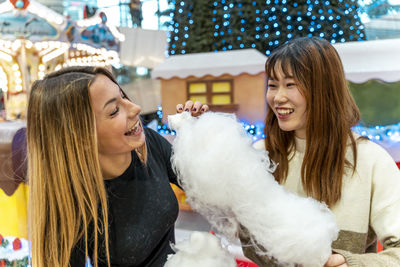 Couple of young multi-ethnic women eating cotton candy at a party. concept of millennial generation