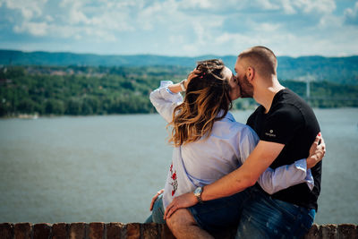 Rear view of couple standing by sea against sky