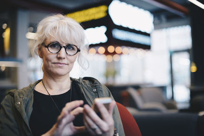 Portrait of confident mature businesswoman using mobile phone in office