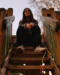 Full length of woman sitting on bench in winter