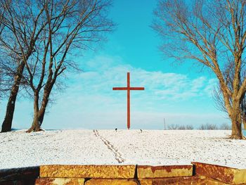 Cross on field against sky during winter