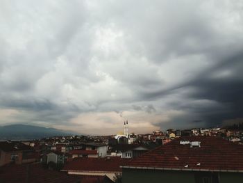 Houses in city against storm clouds