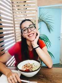Portrait of smiling young woman having food at home