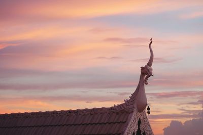 Low angle view of statue by building against sky during sunset