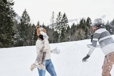 Young couple in winter sweaters having a snowball fight outdoors. snow, happy, fun.