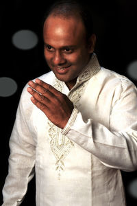 Portrait of smiling man standing against black background