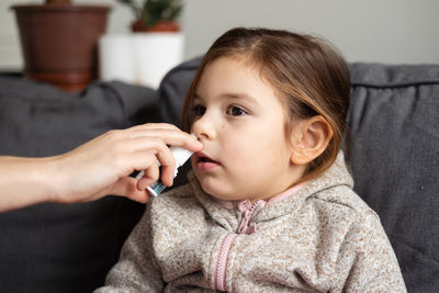 Mother giving nasal spray to daughter at home