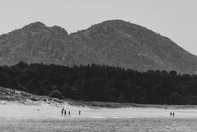 People at beach against clear sky