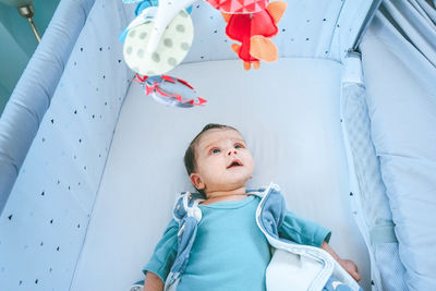 High angle view of baby lying on crib