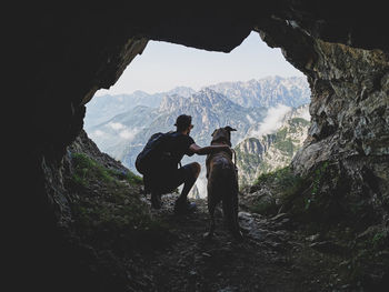 Men and dog on rock against mountains