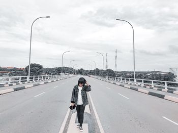 Rear view of woman walking on street against sky