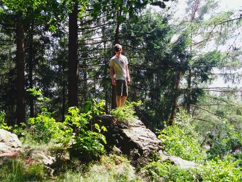 Full length of woman standing on tree trunk in forest