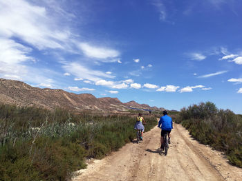 Rear view of man riding motorcycle on road against sky