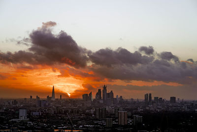 Modern buildings in city against sky during sunset