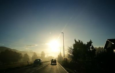 Cars on road against sky during sunset