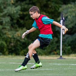 Full length of boy playing soccer on grass