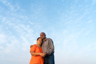 Senior couple standing at the beach together hugging