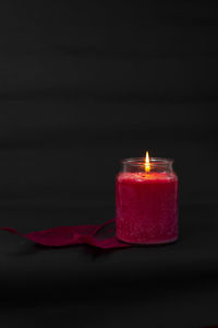 Close-up of lit candle against black background