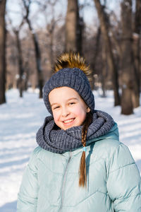 Smiling girl in warm clothes in a winter park on a frosty sunny day. outside walks.