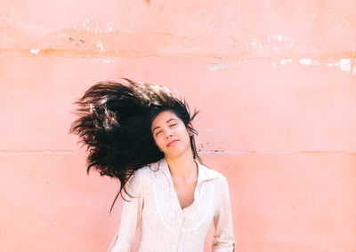 Front view of woman with tousled hair against wall