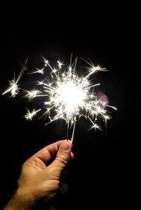 Person hand holding firework display at night