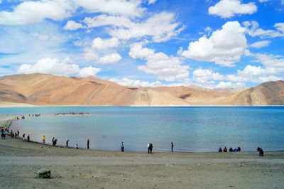 People on beach against cloudy sky