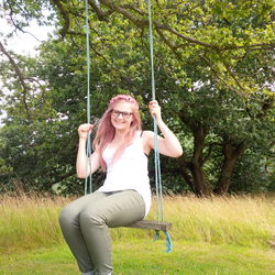 Young woman using phone while sitting on swing