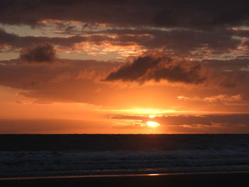 Scenic view of sea against dramatic sky during sunset