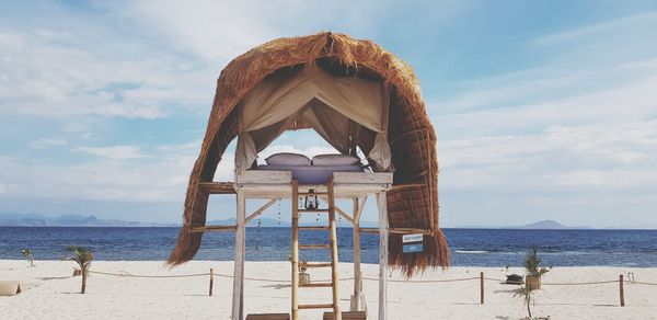 Hut on beach against sky