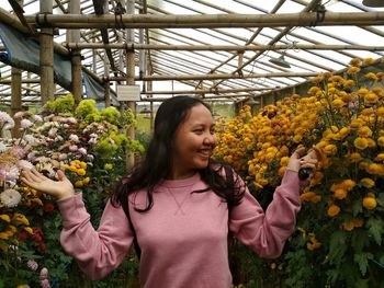 Beautiful young woman standing in greenhouse