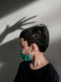 Portrait of young man with face mask against wall