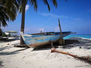 Boat moored on beach against sky