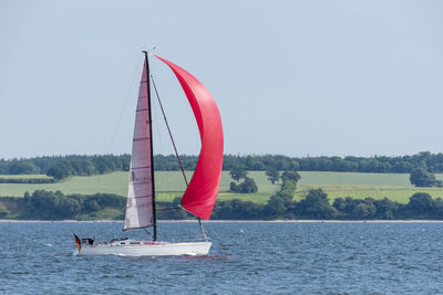 Boat sailing in sea against clear sky