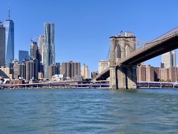 Modern buildings by river against sky in city