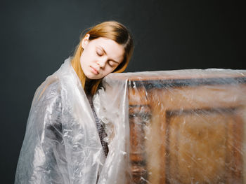 Woman wrapped in plastic against black background