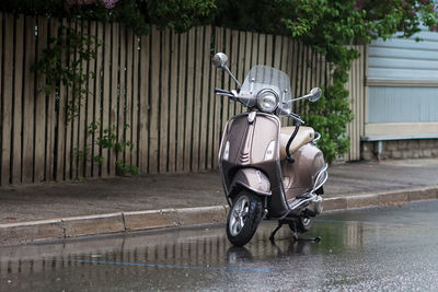 A scooter is parked by a street on a rainy summer day at tallinn, the capital of estonia. 