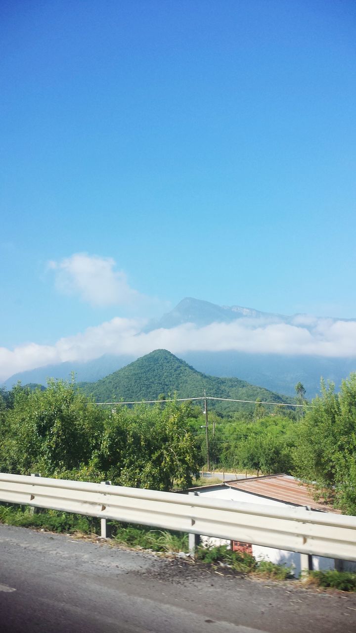 mountain, sky, road, blue, tree, mountain range, tranquil scene, transportation, scenics, tranquility, landscape, beauty in nature, nature, copy space, cloud, day, railing, non-urban scene, outdoors, cloud - sky