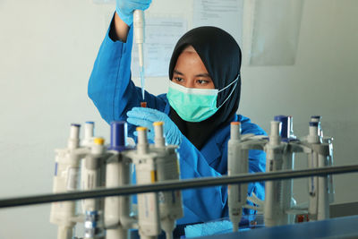 A chemist very carefully drops the ingredient  that has been mixed in the lab into a drug