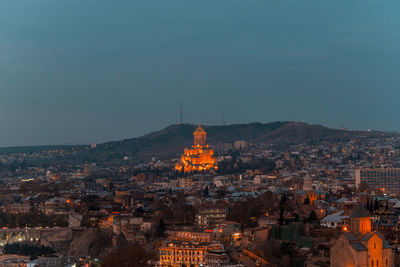 Illuminated buildings in city against sky at dusk