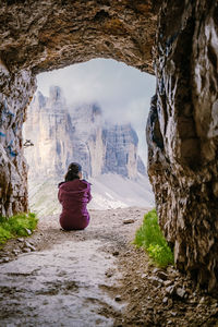 Rear view of woman walking on rock formation during winter