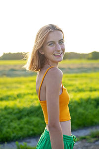 Portrait of young woman standing on field