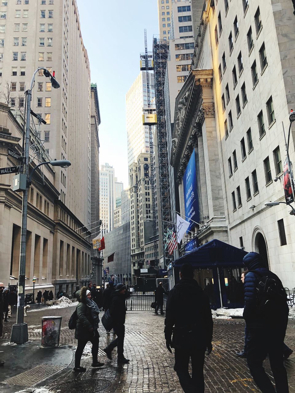 PEOPLE WALKING ON ROAD BY BUILDINGS