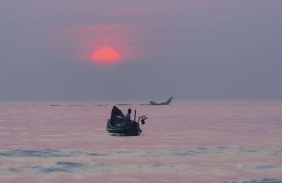 View of horse in sea against sunset sky